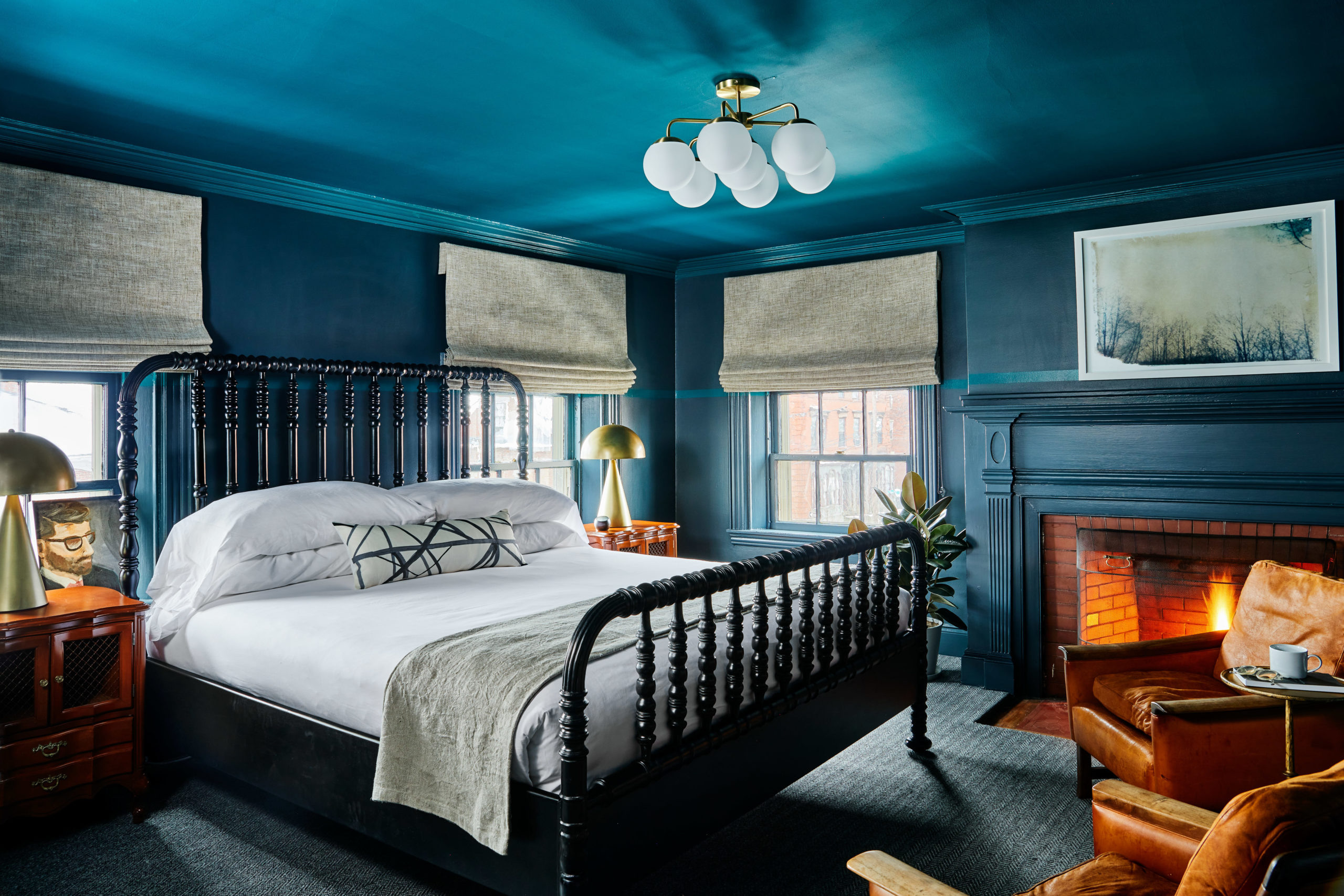 One of the most gorgeous boutique hotels Portland Maine has to offer has walls, ceiling, and fireplace mantle painted the same deep turquoise color, with crisp white linens on the bed and a fire roaring in the fireplace.